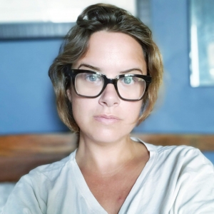a woman in glasses against a multi-textured background