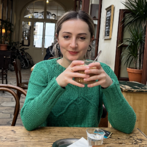 a seated woman smiling while grasping a cup