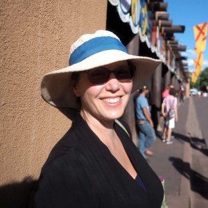 a woman in a white and blue hat and sunglasses smiles