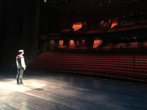 student on Meany stage facing an empty theater