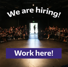 A photo of the inside of a theatre with people in the seats and the words "We are hiring! Work here!" overlaid