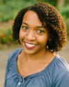a woman with curly brown hair and a blue shirt smiling