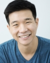 a man with dark hair and a blue shirt smiling