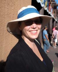 a woman in a white and blue hat and sunglasses smiles