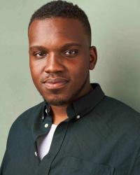 African-American male in a dark green button-up shirt against a mint green background with a soft smile at the camera.