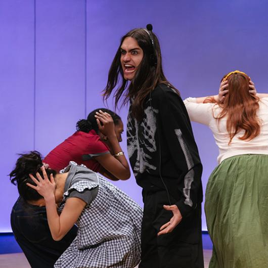 In the play "Everybody," an actor wearing a skeleton suit shouts while other characters cover their ears with their hands. 