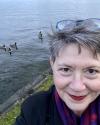 Fran Brown smiling beside a lake with Ducks