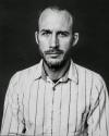 a man in a striped shirt standing in front of a dark background