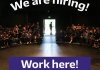 A photo of the inside of a theatre with people in the seats and the words "We are hiring! Work here!" overlaid