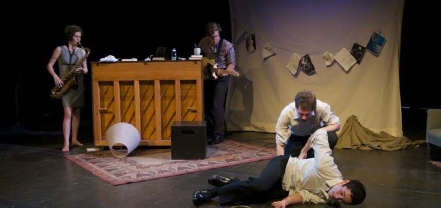 One man lays on the ground near the chalk outline while another sits behind him. A saxaphonist, guitarist, and pianist are playing in the background.