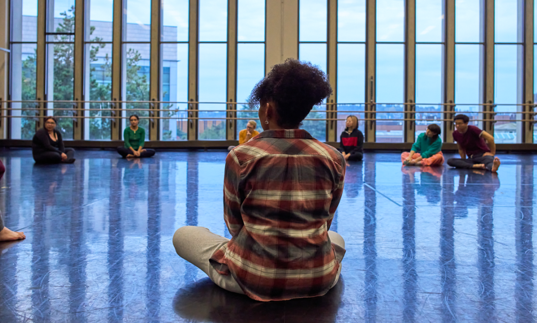 Graduate drama students exploring movement and connection in a collaborative class setting