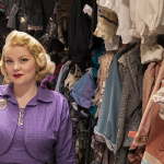 Portrait of Chante Hamann, standing in one of the School of Drama's storage rooms for costumes.