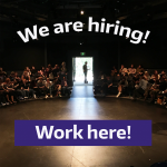 A photo of the inside of a theatre with people in the seats and the words "We are hiring! Work here!" overlaid