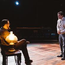 Two men talking in room with. a light