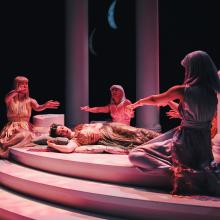 Actors dressed as fairies gather round a sleeping Titania