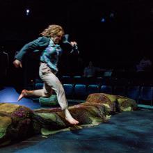 Woman jumps over log onstage