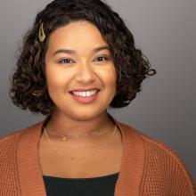 a brunette woman smiling against a gray backround