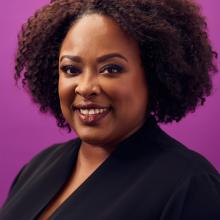 a woman smiling against a purple background