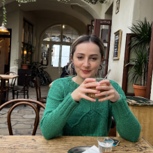 a seated woman smiling while grasping a cup