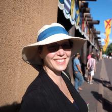 a woman in a white and blue hat and sunglasses smiles
