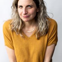 a woman smirking against a light background