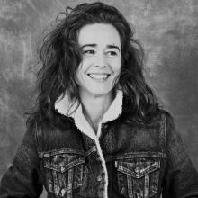 Lara in sherpa lined denim jacket looks to her left, smiling