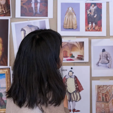 Two people preparing a costume design wall presentation