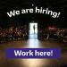 A photo of the inside of a theatre with people in the seats and the words "We are hiring! Work here!" overlaid